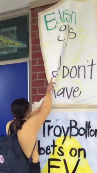 A still from the video of Abbott taking down the poster on Twitter.