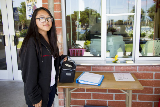 Sara Tajalangit ('16) picks up her lunch from the table in front of the administration building. Photo by Stacey Hall.