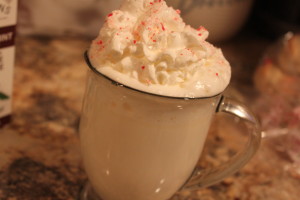 A cup of white hot chocolate topped with whip cream and crush peppermint candies.