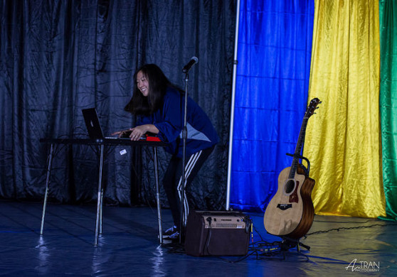 Kelly Truong ('18) grinning while setting up her computer to play her original piece. Photo courtesy of Alex Tran.