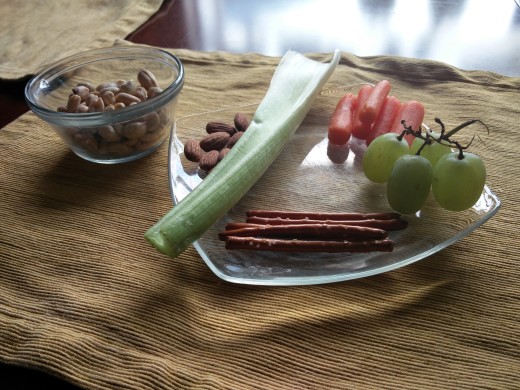 Celery, green grapes, carrots, almonds, pretzels and peanuts beautifully displaying themselves on a very nice glass plate. Photo taken by Benjamin Minch