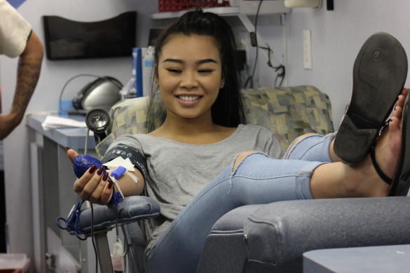 Angela Nguyen ('17) manages a smile despite the pain as she completes her donation. Photo by Ivy Duong