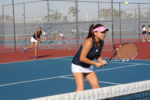 Victoria Nguyen ('18) serves to her Huntington Beach opponents while Clarissa Htay ('17) prepares to return the ball. Photo By Calvin Tran. 