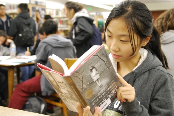 Tracey Huynh ('20) deep into the plot of the most checked out book this school year. Photo by Elise Tran